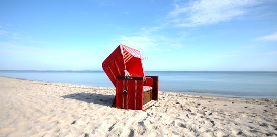 Roter Strandkorb an einem weiten Sandstrand